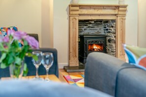 A cozy living room with a stone fireplace, a sofa, and two wine glasses on a table. - 2 Bed in St. Issey (oc-c31993) (Tredinnick)