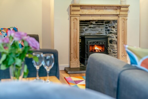 A cozy living room with a stone fireplace, a sofa, and two wine glasses on a table. - 2 Bed in St. Issey (oc-c31993) (Tredinnick)