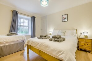 A bedroom with a bed, a bedside table, a nightstand, a window with curtains, and a wall-mounted light fixture. - 2 Bed in St. Issey (oc-c31993) (Tredinnick)