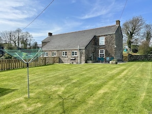 A stone house with a sloped roof and a fenced yard. - 2 Bed in St. Issey (oc-c31993) (Tredinnick)