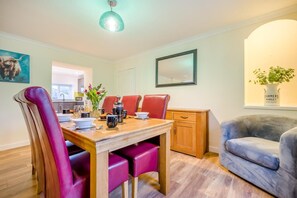 A dining area with a wooden table, red chairs, and a vase with flowers. - 2 Bed in St. Issey (oc-c31993) (Tredinnick)