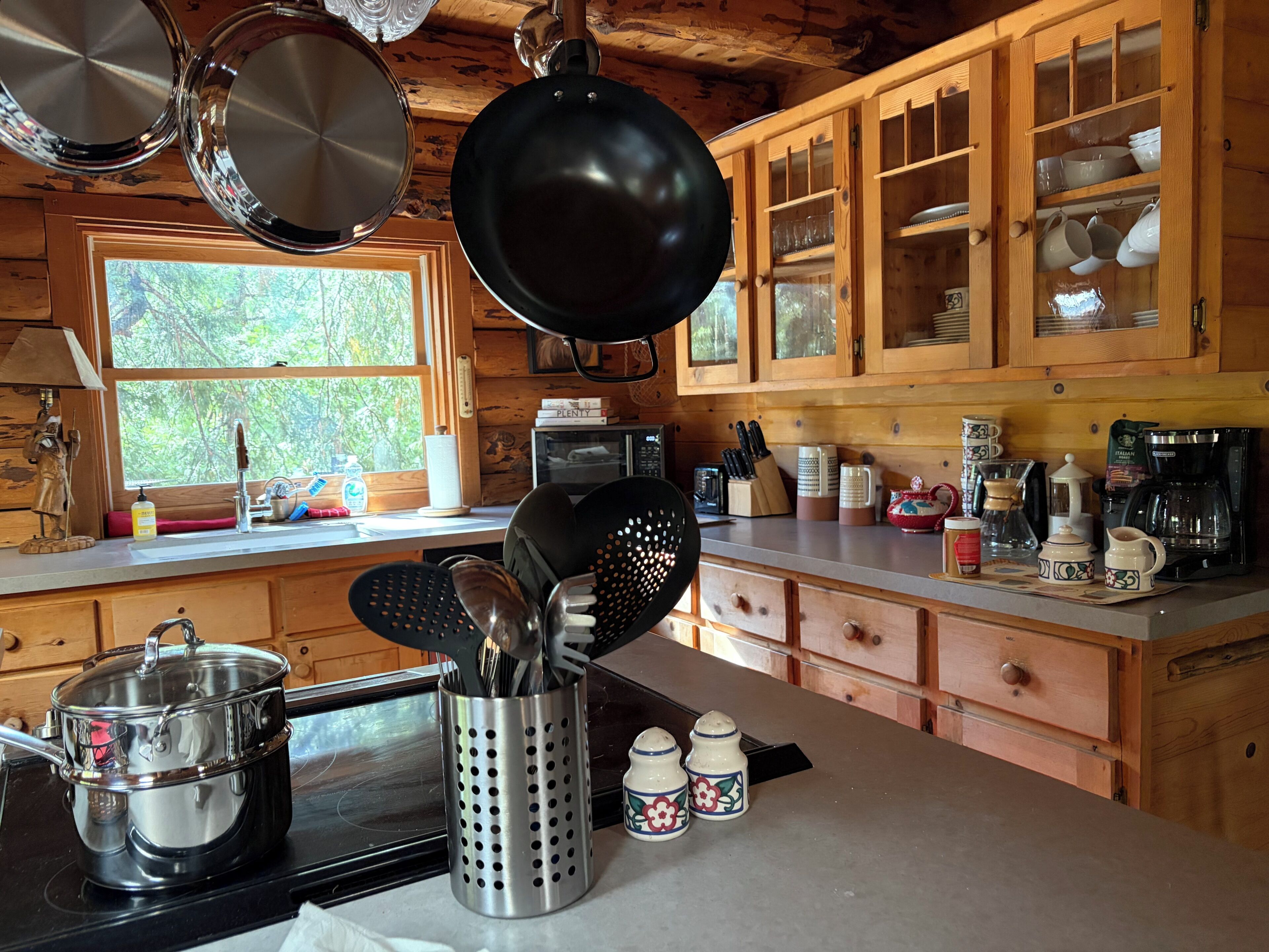 A kitchen with wooden cabinets, a stove, and various kitchen utensils.