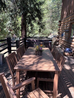 Una terraza de madera con una mesa y sillas, rodeada de árboles.