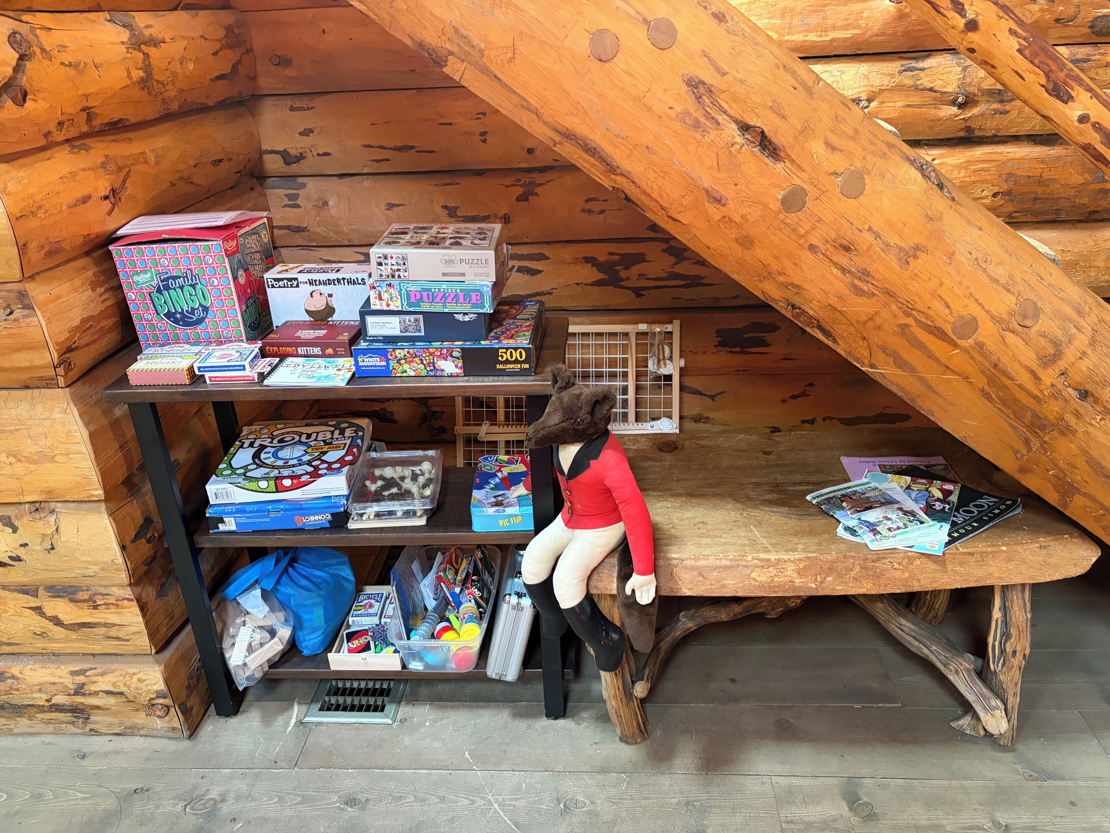 Une mezzanine en bois avec des étagères remplies de jeux de société et de casse-têtes.