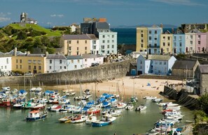 A coastal town with a harbor filled with boats, colorful buildings, and a sandy beach.