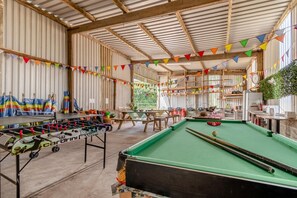 A recreational area with a foosball table, pool table, and various seating arrangements.