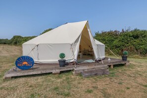 A tent with a wooden deck, two potted plants, and a sign reading 'WEST DALE'.