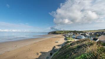 A coastal town with a sandy beach, houses, and a clear sky.