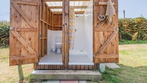A wooden structure with a bathroom and shower area, featuring a toilet, shower curtain, and a towel rack. - 1 Bed in Haverfordwest (oc-b32913) (Dale)