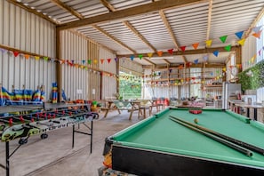 An indoor recreational area with a foosball table, pool table, and various seating arrangements.