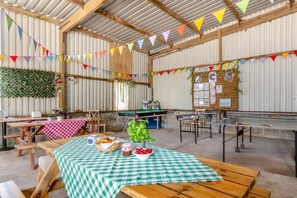 A rustic indoor space with wooden tables, a pool table, and a green checkered tablecloth.
