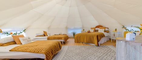 A tent-style accommodation with two beds, a small table, and a window with a view.