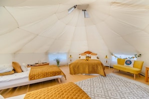A tented accommodation with two beds, a sofa, and a small table.