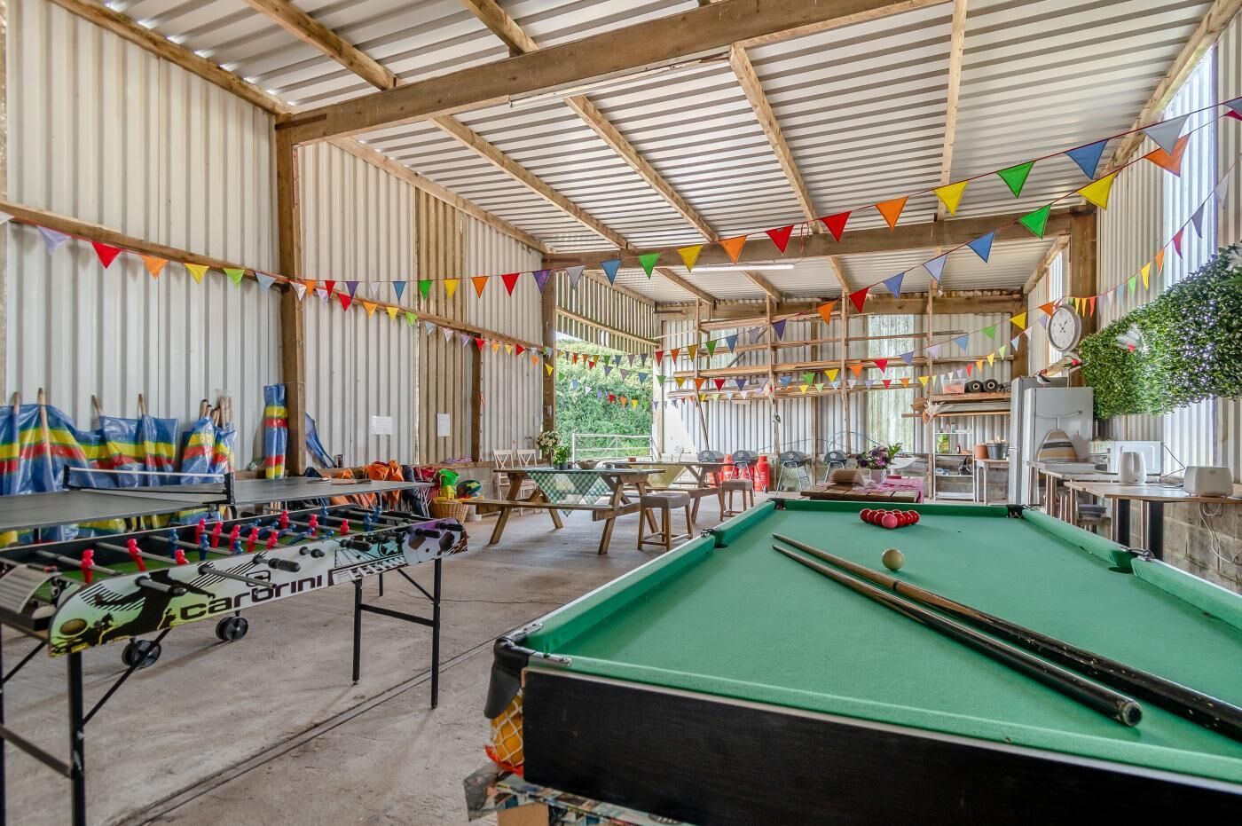 Een binnenrecreatiegebied met een tafelvoetbaltafel, een pooltafel en diverse zithoeken.
