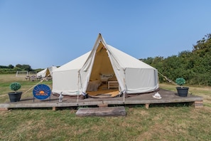 A tent with an open entrance, a picnic table, and a sign with a logo.