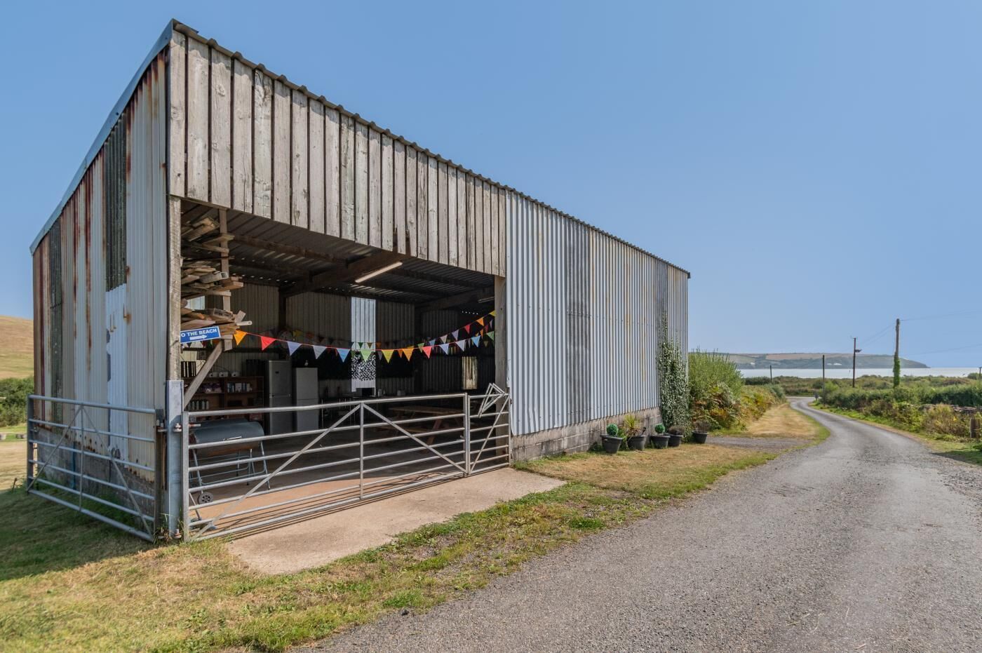 A metal building with a covered entrance, a gravel path leading to it, and a sign indicating a beach direction.