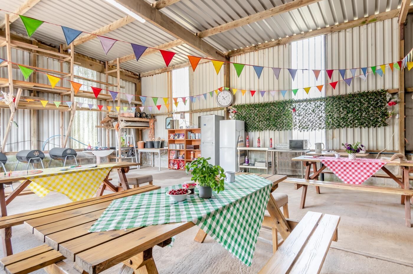 A rustic interior with wooden tables and benches, a clock, and colorful bunting.