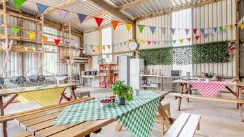A rustic interior with wooden tables and benches, a clock, and colorful bunting.