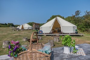 A campsite with tents, picnic tables, and outdoor furniture.