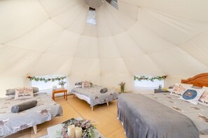 A tented accommodation with two beds, a table, and a small seating area.