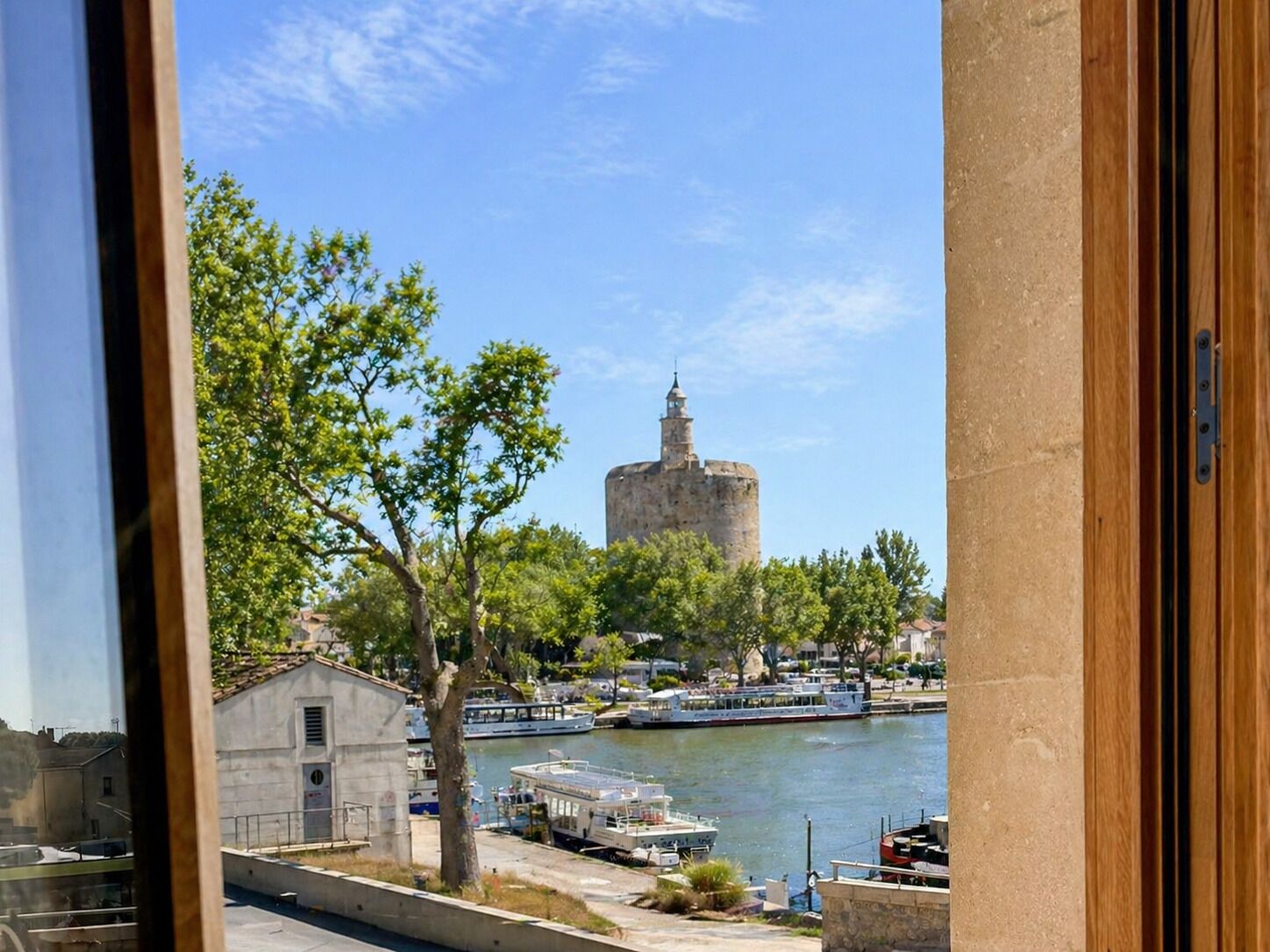 A view of a historic tower by a river with boats docked nearby.