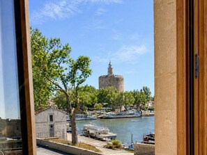 A view of a historic tower by a river with boats docked nearby. - Le Palmier Aigues-Mortes Petite Camargue (Aigues-Mortes)