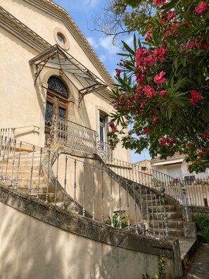A building with a staircase leading to a door with a decorative glass window. - Le Palmier Aigues-Mortes Petite Camargue (Aigues-Mortes)