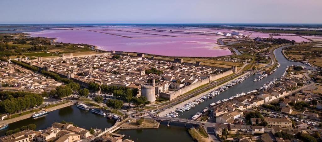 An aerial view of a historic town with a river, a castle, and a marina.