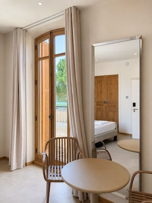 Una habitación de hotel con una cama, una mesa redonda, una silla y un espejo grande.