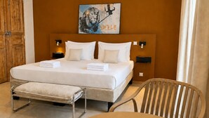 Habitación de hotel con una cama grande, mesitas de noche, una silla y un cuadro en la pared.