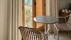 Una habitación con un amplio ventanal corredero, una mesa redonda, dos sillas, un televisor y vistas al exterior.