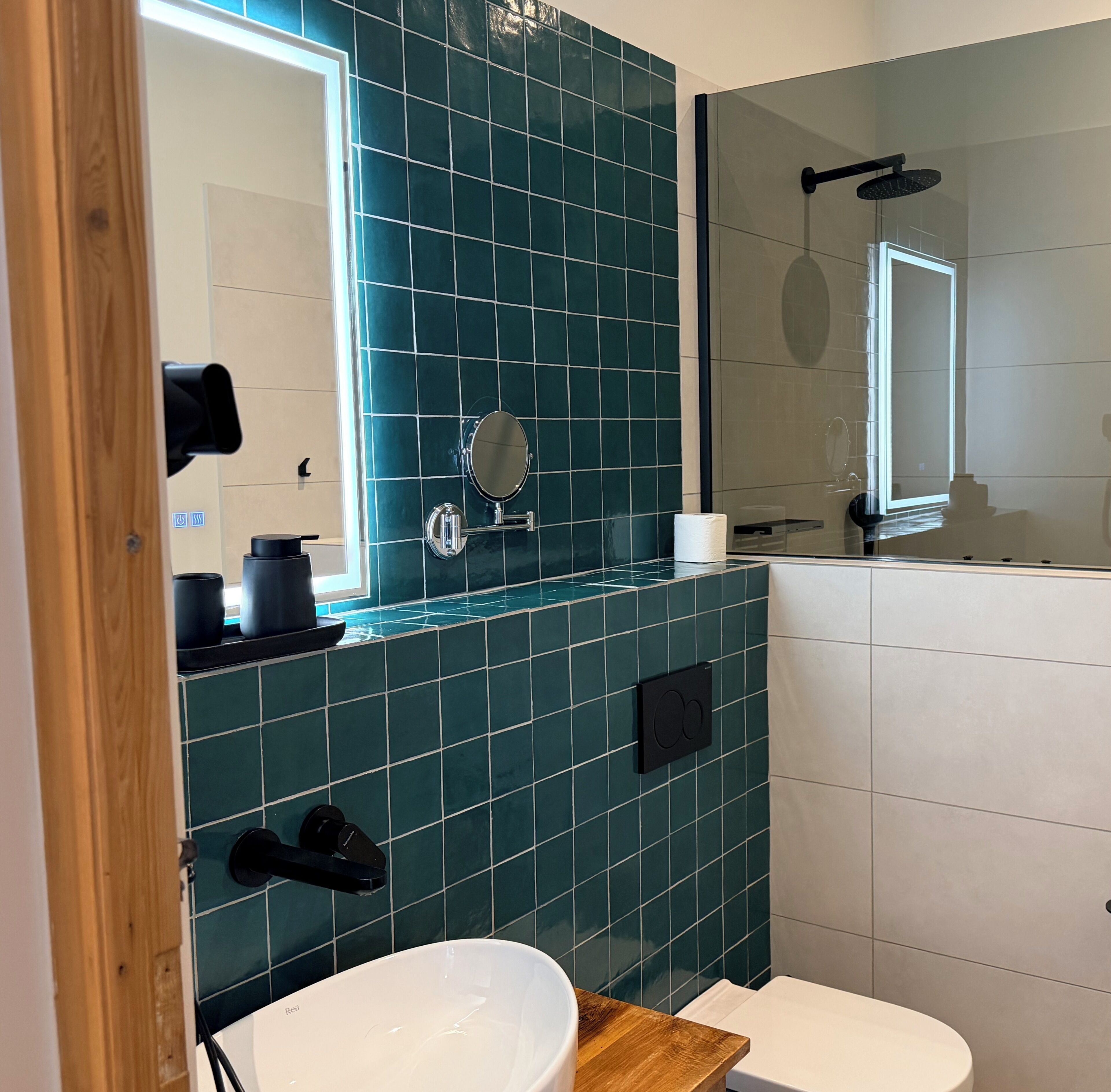 A bathroom with a white toilet, a mirror, and a shower area.