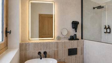 Uma casa de banho moderna com um espelho grande, uma sanita redonda, uma sanita e uma cabine de duche.