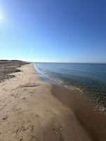 Una playa con cielo despejado, una orilla arenosa y huellas.