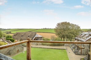 A rural landscape with a thatched-roof building, a large tree, and a view of the surrounding fields. - 3 Bed in Blackawton (oc-c32809) (Blackawton)