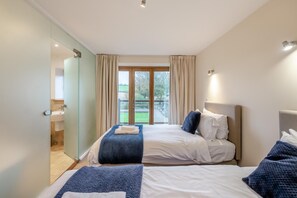 Ein Hotelzimmer mit zwei Betten, einem Badezimmer und einem Balkon mit Vorhängen.