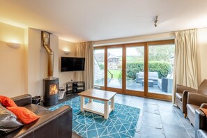 Ein Wohnzimmer mit Kamin, Fernseher und Blick ins Freie.