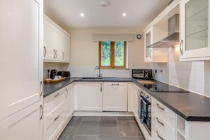A modern kitchen with white cabinets, a black countertop, and a window with a view of greenery. - 3 Bed in Blackawton (oc-c32809) (Blackawton)