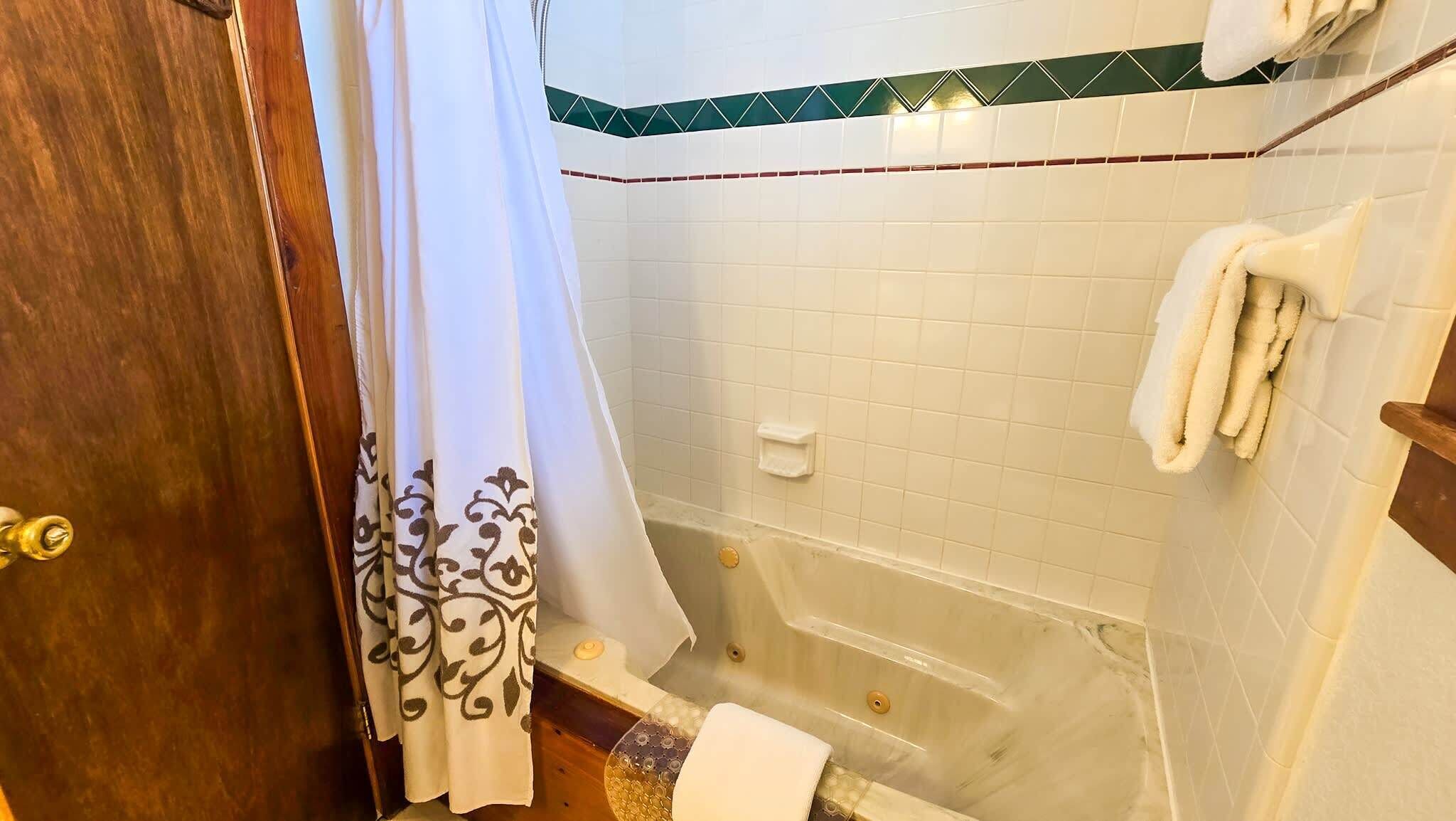 A bathroom with a bathtub, a shower curtain, and a towel rack.