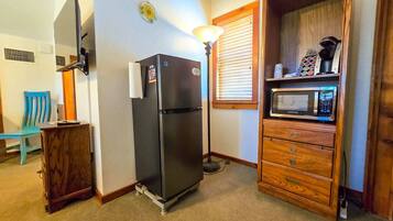 Cocina compacta con refrigerador, microondas y armario de madera.