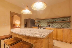 A kitchen with a central island, wooden cabinets, a herringbone backsplash, and pendant lighting. - Bella Verde, Steps to beach, shops and restaurants (San Francisco)