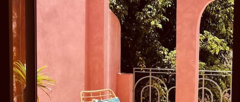 A patio with wicker furniture, a tiled floor, and a view of trees through arches.