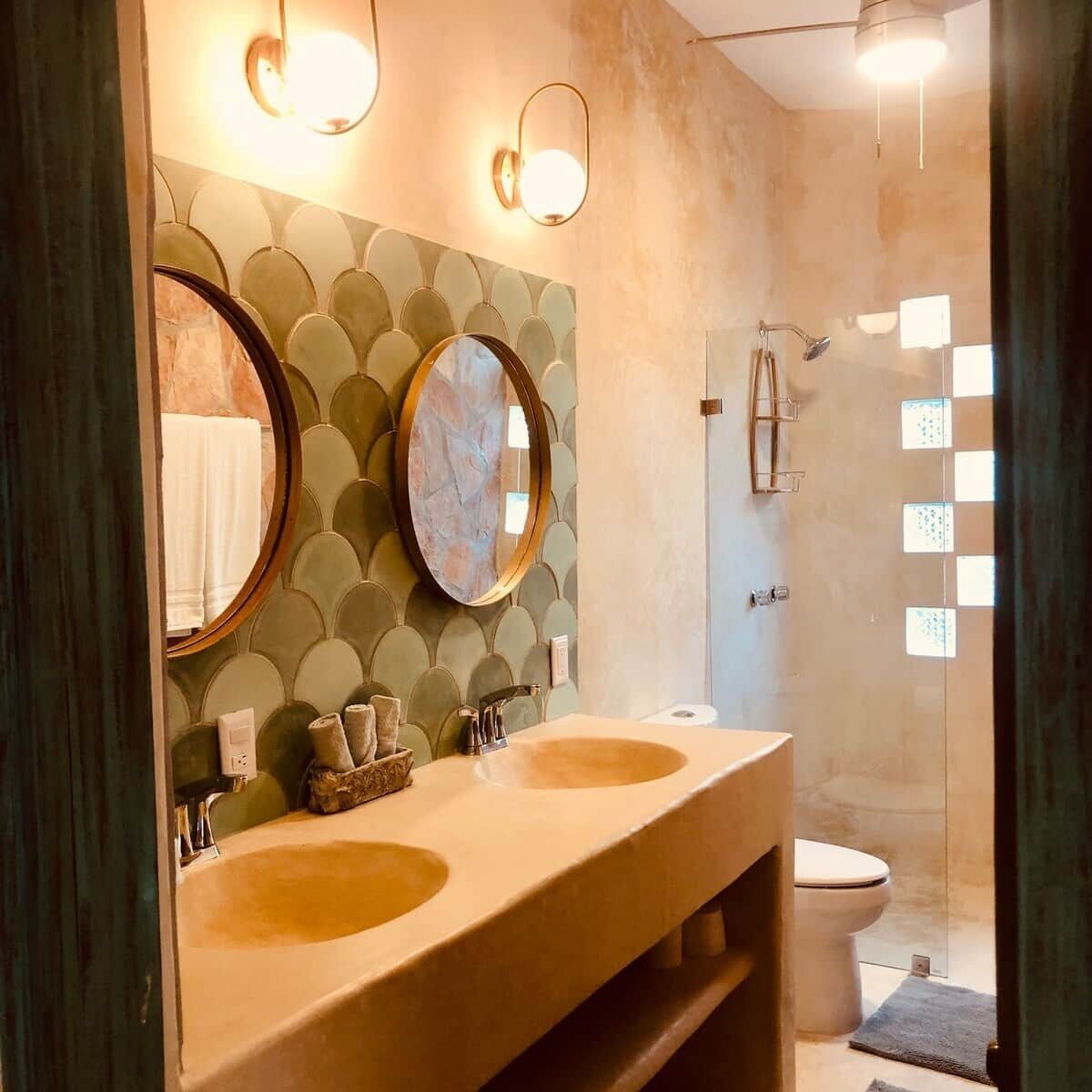 A bathroom with two sinks, a mirror, and a shower.