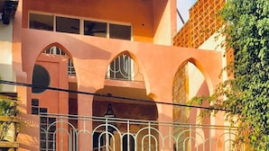 Ein zweistöckiges Gebäude mit einem Balkon, einem verzierten Tor und einem geparkten Auto.
