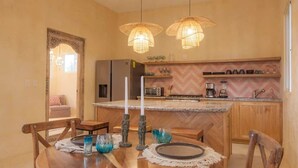 A kitchen with a central island, wooden cabinets, and pendant lighting. - Bella Rosa, center of town, steps to the beach. (San Francisco)