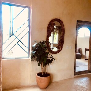 A room with a large window, a potted plant, and two mirrors on the wall. - Bella Rosa, center of town, steps to the beach. (San Francisco)