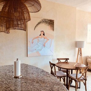 A dining area with a granite countertop, wooden chairs, a white vase, and a painting of a woman in a white dress. - Bella Rosa, center of town, steps to the beach. (San Francisco)