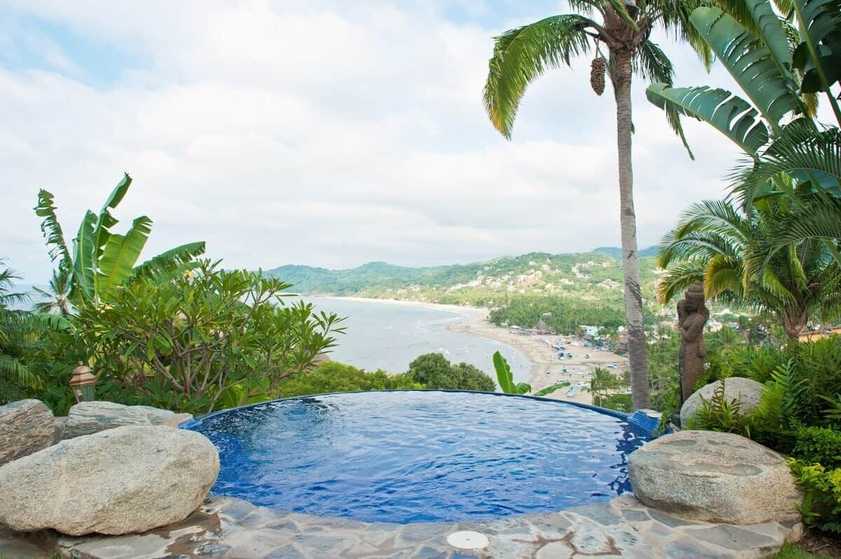 Ein Infinity-Pool mit Blick auf Strand und Berge.