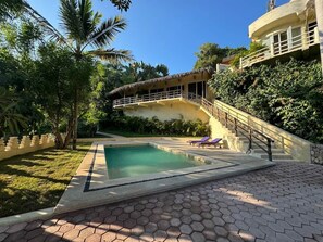 A swimming pool with a staircase leading to a building, surrounded by greenery. - Romantic Jungle Bungalow w/ Pool Near Town & Beach (Sayulita)