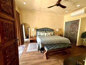 A bedroom with a large bed, a bench, a ceiling fan, and a decorative door. - Romantic Jungle Bungalow w/ Pool Near Town & Beach (Sayulita)